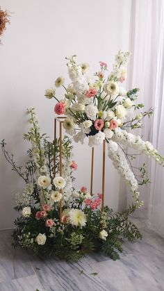 an arrangement of white and pink flowers on a stand