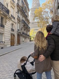 two women and a child are walking down the street in front of the eiffel tower