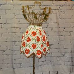 a dress on a stand in front of a white brick wall with a red flowered design