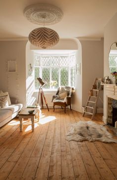 a living room filled with furniture and a fire place next to a window on top of a hard wood floor