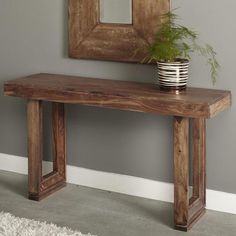 a wooden bench sitting next to a mirror and plant on top of a white rug