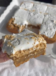 a person holding up a piece of cake with icing on it in their hand