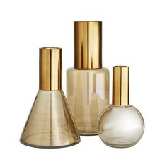 three glass vases with gold caps on them are sitting next to each other in front of a white background