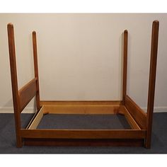 a wooden bed frame sitting on top of a carpeted floor next to a wall