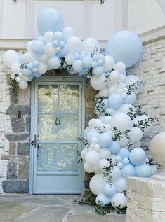 blue and white balloons are attached to the front door of a house with an arch