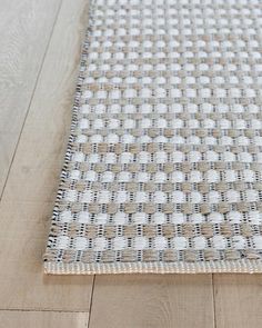 a close up of a rug on a wooden floor with white and brown squares in the middle