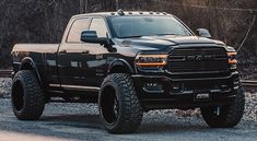 a large black truck parked on top of a gravel road