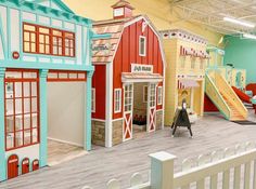 an indoor play area with wooden floors and colorful painted buildings on the walls, along with a slide