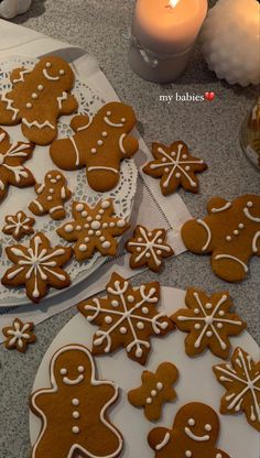 gingerbread cookies are on plates next to a lit candle and some glass vases