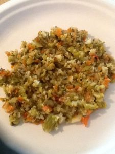 a white plate topped with rice and carrots on top of a wooden table next to a knife