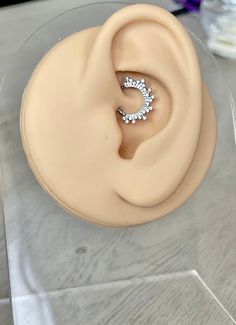 a pair of earring sitting on top of a clear plastic container next to a purple flower