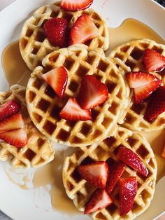 three waffles with strawberries on top sit on a plate