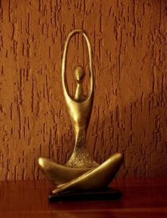 a gold statue sitting on top of a wooden table next to a red brick wall