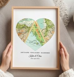 a person holding up a framed heart shaped map