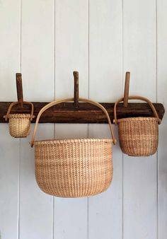 two wicker baskets hanging from a wooden wall with hooks on the back and sides