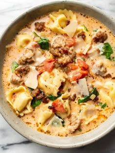 a bowl filled with pasta, meat and cheese on top of a marble countertop