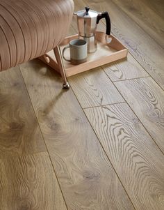 a wooden floor with a chair and coffee pot on it's tray next to a couch