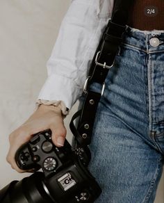 a person holding a camera in their right hand and wearing a belt around his waist