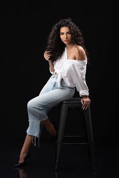 a beautiful woman sitting on top of a stool