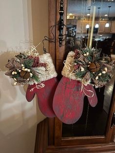 two christmas stockings hanging on a door with holly wreaths and pine cones in them