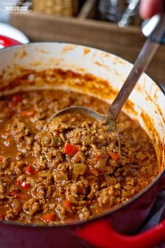 a large pot full of chili and meat with a ladle in the bottom right hand corner