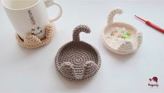 two crocheted animals sitting next to each other near a coffee cup and mug