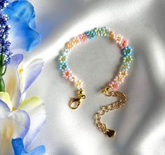 a close up of a bracelet on a white cloth with flowers in the foreground