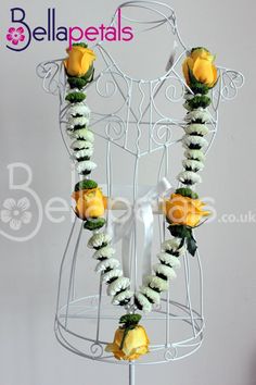 a white mannequin with yellow roses and greenery on it's neck