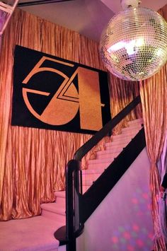 a disco ball hanging from the ceiling next to a stair case with curtains on it