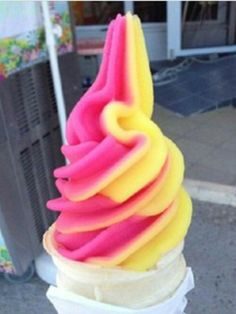 an ice cream cone with pink, yellow and orange swirls on it's top