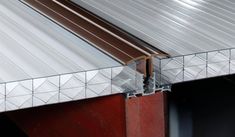 a close up of a metal roof on a building with red wood and white tiles