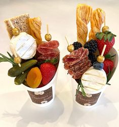 two cups filled with different types of food on top of a white table next to each other