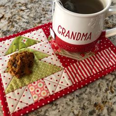 a cup of coffee sitting on top of a red and white place mat next to a cookie