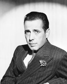 a black and white photo of a man in a suit with a flower on his lapel