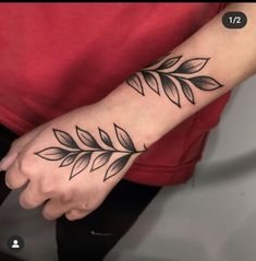 a black and white photo of a person's wrist with leaves on it