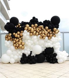 black and white balloons with gold foiled ones on the outside of a large building