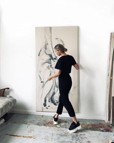 a woman is walking in front of a painting