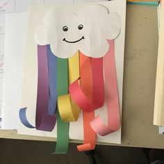 a piece of paper that has been cut out to look like a cloud and rainbow streamers