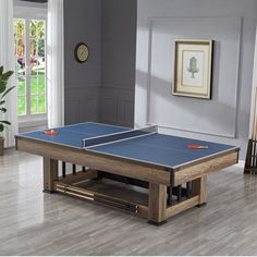 a ping pong table in the middle of a living room with hardwood floors and gray walls