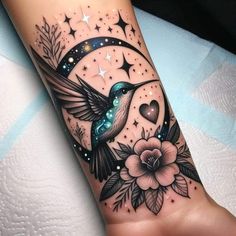 a tattoo with a humming bird on it's arm and stars in the sky