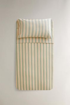 a white and blue striped bed spread on top of a wooden floor next to a wall