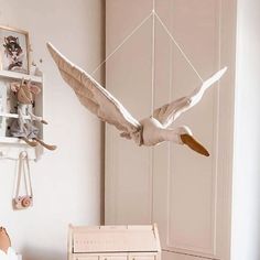 a white bird is flying in the air above a bed and dresser with stuffed animals on it