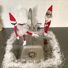 two elfs standing in the sink with snow all over them