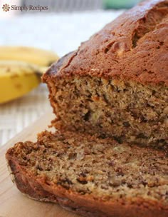 a loaf of banana bread sitting on top of a cutting board next to a banana