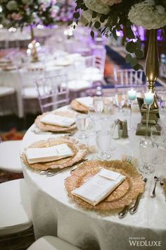 the table is set with white and gold plates, silverware, and napkins