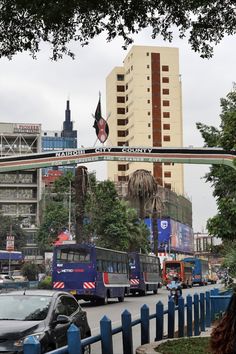 two double decker buses driving down the street in front of tall buildings and palm trees