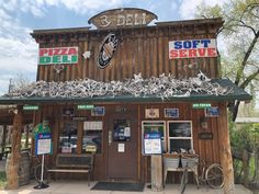 the front of a pizza shop with lots of signs on it's roof and windows