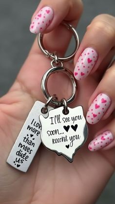 a woman's hand holding a keychain with pink and white hearts on it