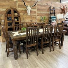 a dining room table and chairs in front of a cow skull on the wall behind it