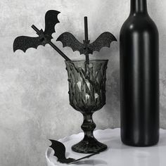 a bottle and glass with bats in it on a table next to a bat decoration